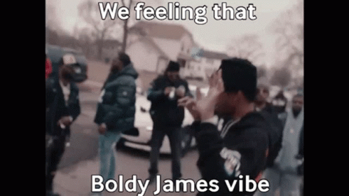 A Man Is Standing In Front Of A Crowd Of People And Covering His Face . GIF