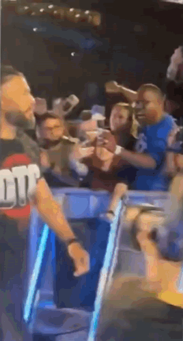 A Man Is Standing In Front Of A Crowd Of People In A Stadium . GIF