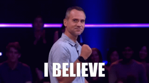 A Man Is Standing In Front Of A Crowd With The Words `` I Believe '' Written On His Chest . GIF