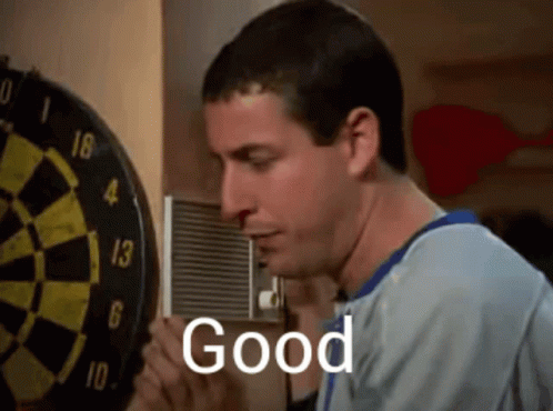 A Man Is Standing In Front Of A Dart Board With The Word Good Written On It GIF