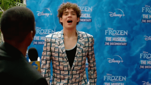 a man is standing in front of a disney frozen sign