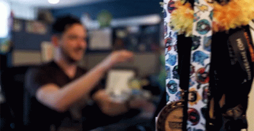 A Man Is Standing In Front Of A Display Of Medals And Lanyards . GIF