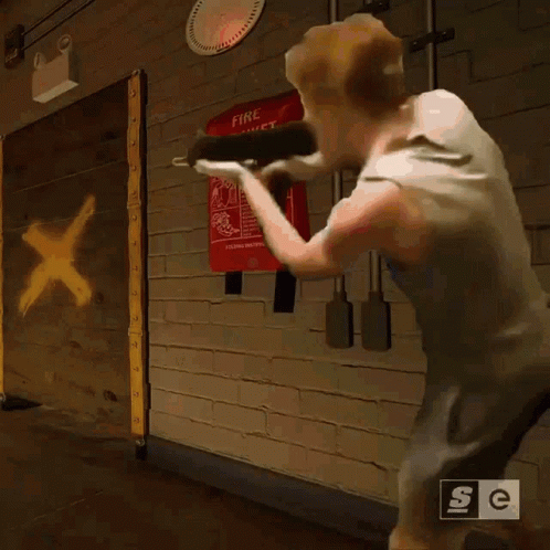 A Man Is Standing In Front Of A Fire Blanket Sign GIF