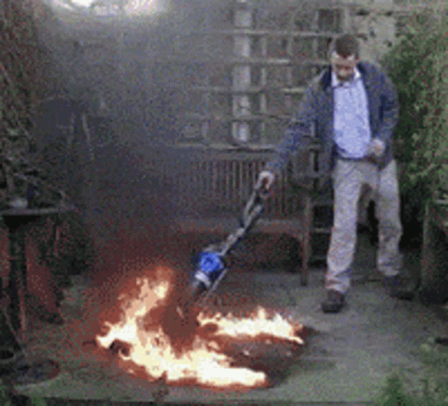 A Man Is Standing In Front Of A Fire Pit GIF