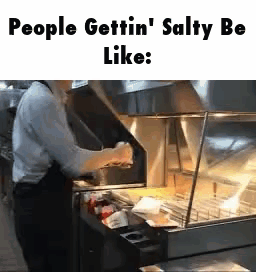 A Man Is Standing In Front Of A Fryer In A Restaurant And Cooking Food . GIF