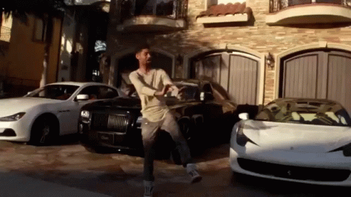 A Man Is Standing In Front Of A Garage Full Of Cars GIF