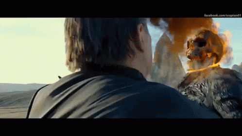 A Man Is Standing In Front Of A Ghost Rider With A Skull On It 'S Head GIF