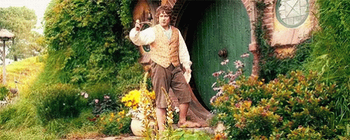 A Man Is Standing In Front Of A Green Door In A Garden Holding A Sword . GIF