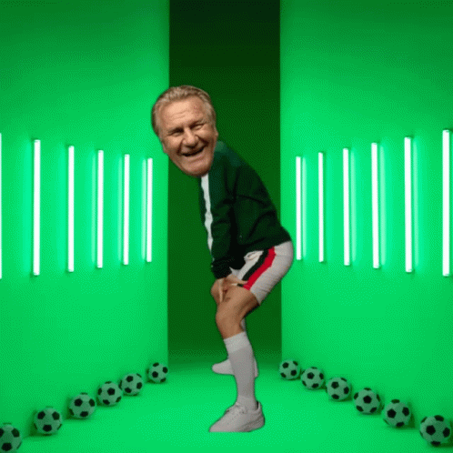 A Man Is Standing In Front Of A Green Wall With Soccer Balls GIF