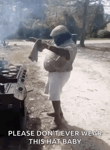 A Man Is Standing In Front Of A Grill Holding A Towel And Says Please Don 'T Ever Wear This Hat Baby GIF