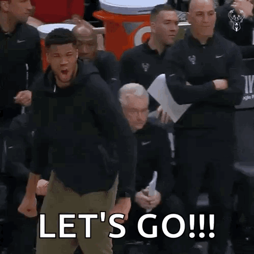 A Man Is Standing In Front Of A Group Of Men And Shouting Let 'S Go . GIF