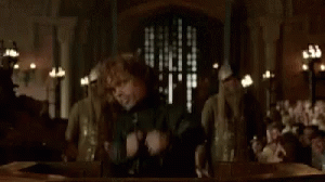 A Man Is Standing In Front Of A Group Of People Holding A Sword . GIF