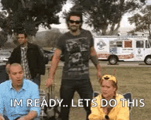 A Man Is Standing In Front Of A Group Of People While A Woman Sits In A Chair . GIF