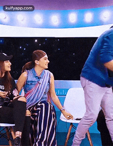 A Man Is Standing In Front Of A Group Of Women Sitting In Chairs On A Stage . GIF