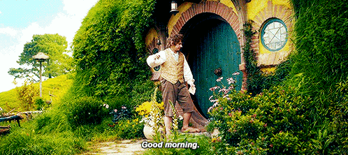 A Man Is Standing In Front Of A House With A Green Door . GIF