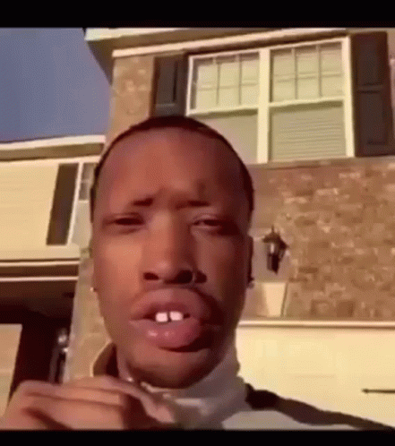 A Man Is Standing In Front Of A House With His Mouth Open . GIF