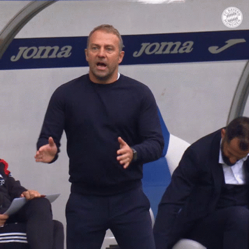 A Man Is Standing In Front Of A Joma Sign GIF