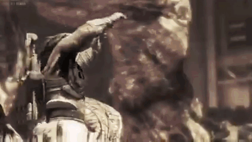 A Man Is Standing In Front Of A Large Rock In A Dark Room . GIF