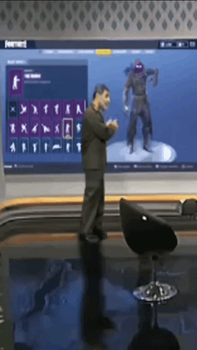 A Man Is Standing In Front Of A Large Screen With A Ninja On It GIF