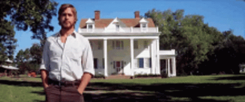 A Man Is Standing In Front Of A Large White House GIF