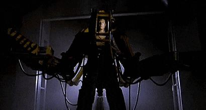A Man Is Standing In Front Of A Machine That Looks Like A Robot With Wings . GIF