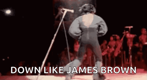 A Man Is Standing In Front Of A Microphone On A Stage And Singing . GIF