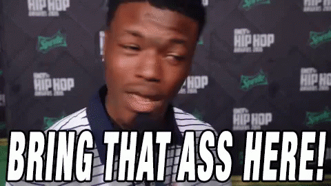 A Man Is Standing In Front Of A Microphone With The Words `` Bring That Ass Here '' . GIF