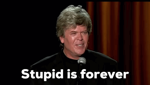 A Man Is Standing In Front Of A Microphone With The Words `` Stupid Is Forever '' Written On The Screen . GIF