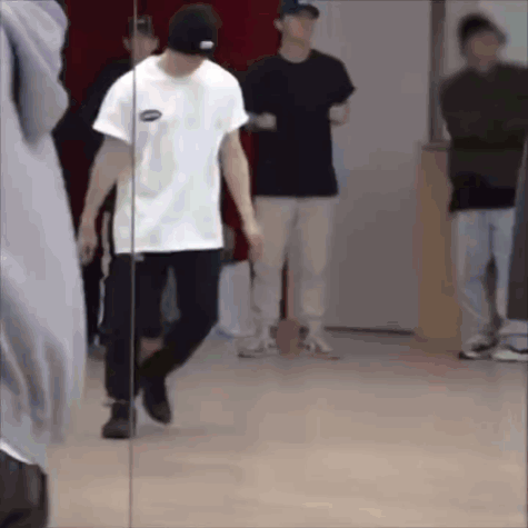 A Man Is Standing In Front Of A Mirror In A Dance Studio . GIF