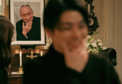 A Man Is Standing In Front Of A Picture Of A Man GIF