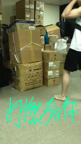 A Man Is Standing In Front Of A Pile Of Boxes With The Word Lg On Them GIF