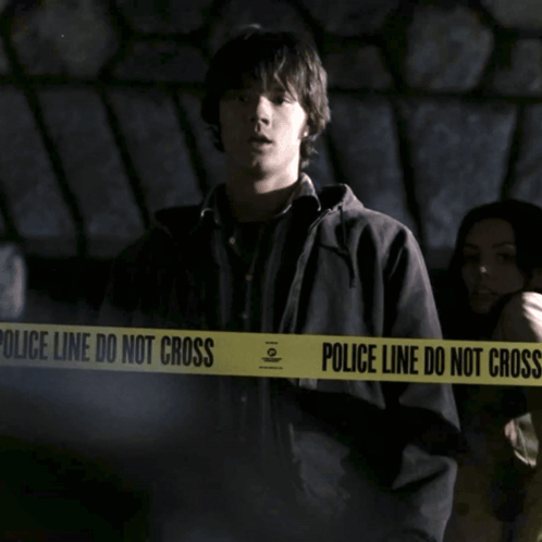 A Man Is Standing In Front Of A Police Line Do Not Cross Tape GIF