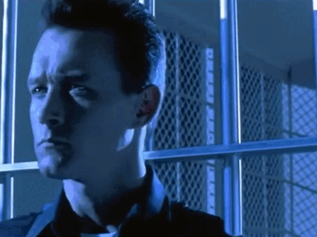 A Man Is Standing In Front Of A Prison Cell With Bars GIF