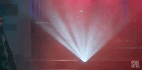 A Man Is Standing In Front Of A Projector Screen In A Dark Room With A Red Background . GIF