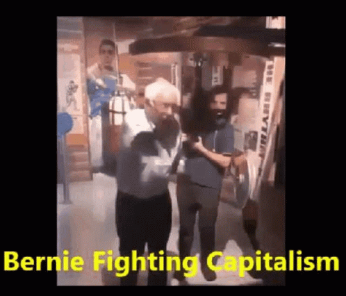 A Man Is Standing In Front Of A Punching Bag With The Words `` Bernie Fighting Capitalism '' . GIF