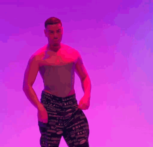 A Man Is Standing In Front Of A Purple Background With His Hands Folded . GIF