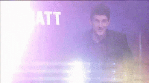 A Man Is Standing In Front Of A Purple Background With The Word Matt In White Letters GIF