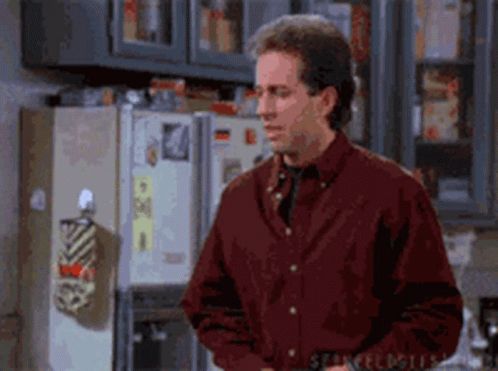 A Man Is Standing In Front Of A Refrigerator In A Kitchen . GIF