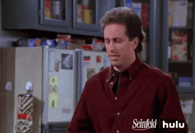 A Man Is Standing In Front Of A Refrigerator In A Kitchen . GIF