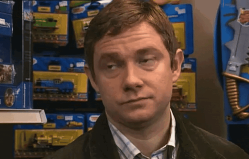 A Man Is Standing In Front Of A Shelf Full Of Toy Trains GIF