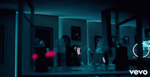 A Man Is Standing In Front Of A Shelf Full Of Trophies And A Sign That Says Vevo On It GIF