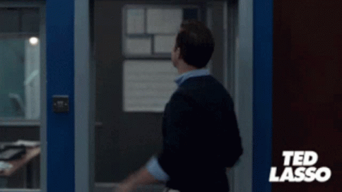 A Man Is Standing In Front Of A Sign That Says Believe On It . GIF