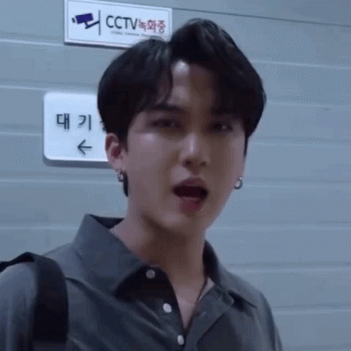 A Man Is Standing In Front Of A Sign That Says Cctv On It . GIF
