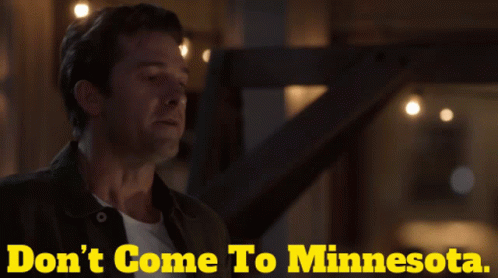 A Man Is Standing In Front Of A Sign That Says " Don 'T Come To Minnesota " GIF