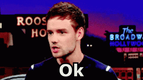 A Man Is Standing In Front Of A Sign That Says Roos Hollywood GIF