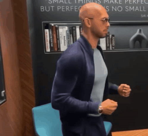 A Man Is Standing In Front Of A Sign That Says Small Things Make Perfect But Perfection Is No Small Thing GIF