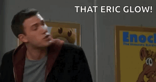 A Man Is Standing In Front Of A Sign That Says " That Eric Glow ! Survey Says ! " GIF