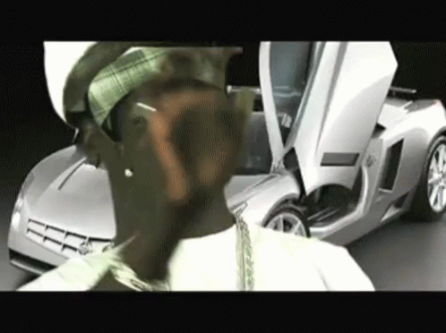 A Man Is Standing In Front Of A Silver Sports Car GIF