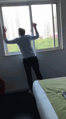 A Man Is Standing In Front Of A Sliding Glass Window GIF