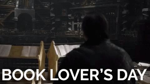A Man Is Standing In Front Of A Stack Of Books In A Library . GIF